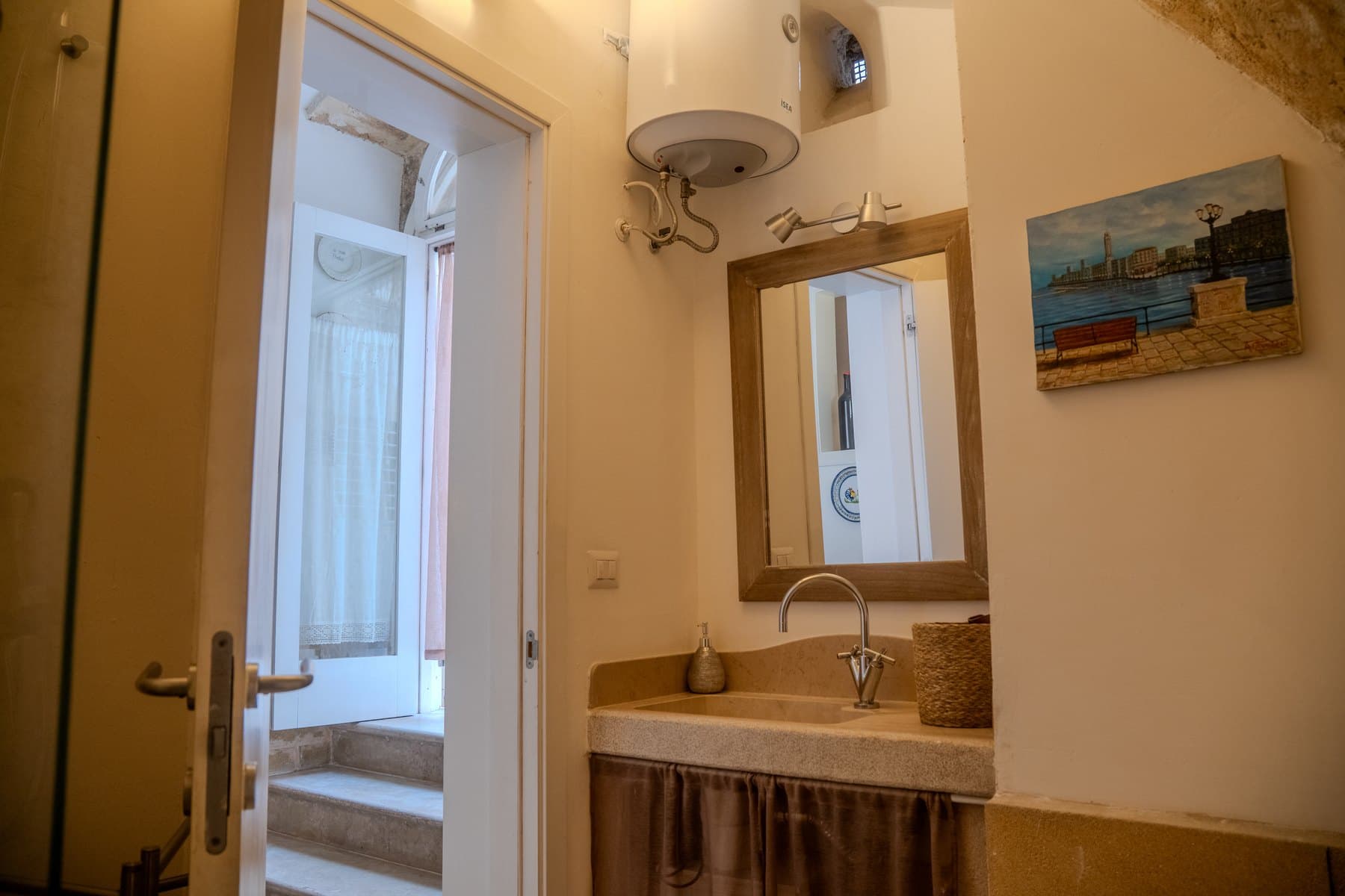 Il lavabo in pietra con lo specchio e un dipinto del lungomare di Bari